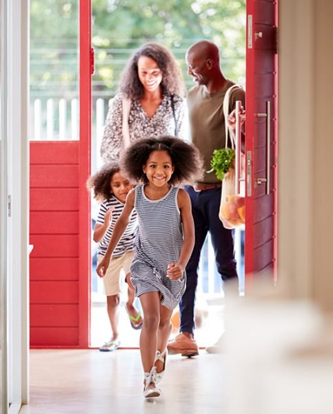 Family Returning Home From Shopping Trip Using Plastic Free Grocery Bags Opening Front Door