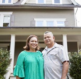 Portrait Of Smiling Senior Couple In Front Of Their Home